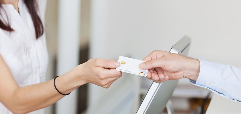 Patient handing a payment card across the front desk